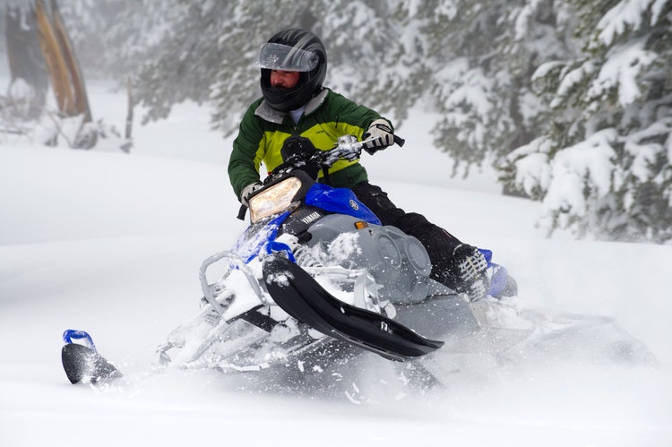 Man crashing through snow on a snowmobile